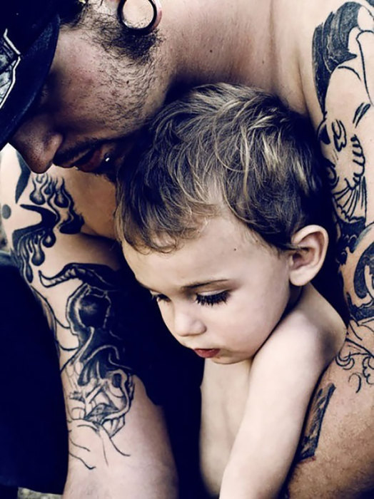 Малыш рассматривает папины татуировки.